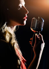 Sensual woman with red lips sings into a microphone. The singer records the song in a professional...