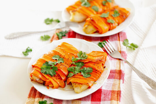White fish fillet baked with carrots on a plate. Food photography