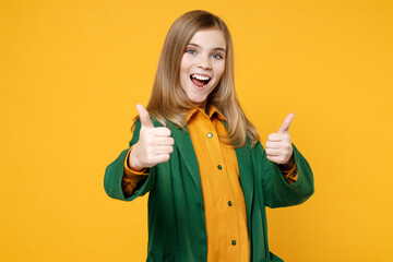Little blonde happy smiling kid girl 12-13 years old wearing casual clothes green shirt show thumb up gesture isolated on yellow orange background children studio portrait Childhood lifestyle concept