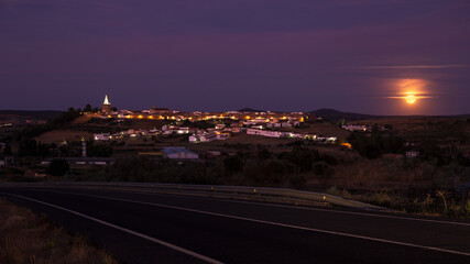 Night landscape of town with moon and road in the foreground