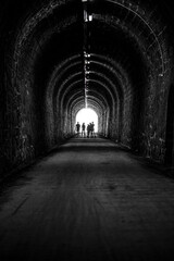 Fototapeta na wymiar silhouettes of human beings in backlight at the end of a dark tunnel