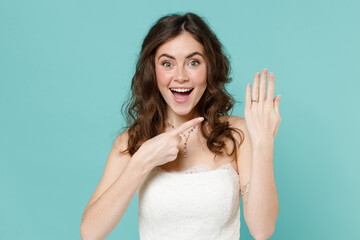 Excited surprised bride young woman in beautiful white wedding dress pointing index finger on hand...