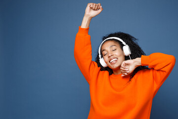 Attractive young african american woman in casual bright orange sweatshirt listening music with...