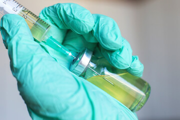 Vial filled with liquid vaccine in medical lab with syringe.doctor's hand holds ampoule and syringe