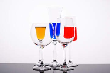 red blue and yellow liquor syrups in glass glasses on white background
