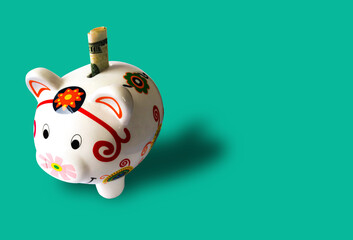 piggy bank with a twenty usd bancknote in a aquamarine banckground