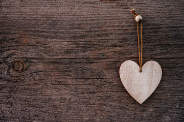 Valentine's Day background. Brown natural boards in grunge style with one wooden decorative hearts. Top view. Surface of table to shoot flat lay. Concept love, romantic relation. Copy space for text