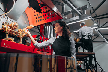 Barista checking the coffee beans in factory machine. Bottom view.