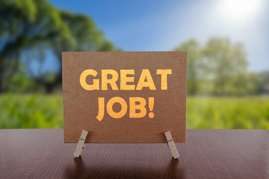 Great job text on card on the table with sunny green park background.