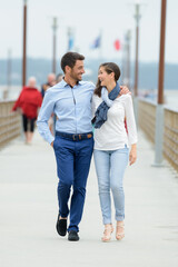 a couple walking on a pier on a lakeside