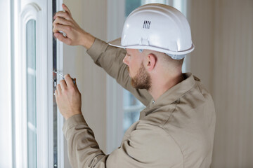 man using screwdriver on window