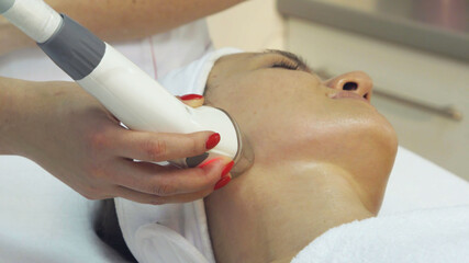 Young woman undergoing procedure of rf lifting in beauty salon, close up
