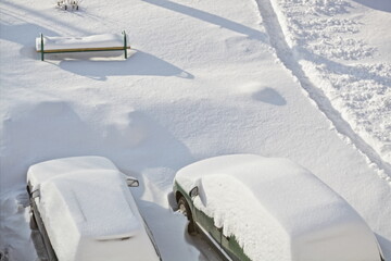 Two snow covered cars on Parking on snowdrifts background top view at Sunny winter day