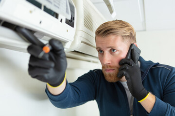 male technician repairing air conditioner outdoors