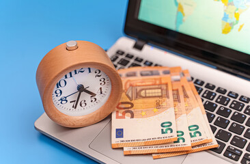 Time is money! Clock with euro banknotes on notebook.