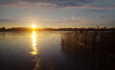 Obraz premium Winter sunset with reflection of sun on ice on the frozen lake