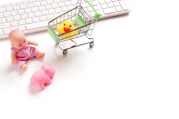Baby store online flat lay composition photography. Child toy internet shop. Computer keyboard, doll, cart, yellow rubber duck and pink hippo. Mockup, free space for text - Powered by Adobe