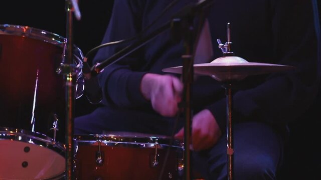 drummer playing drum kit. Hands of a musician drummer holding drumsticks hitting a cymbal on a dark background, close-up. Drum cymbal vibration.