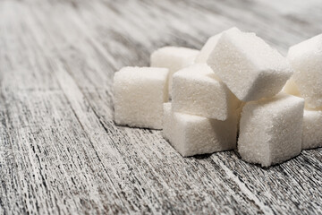 Sugar cubes lie on a wooden background of gray color. Sugar. Refined cane sugar