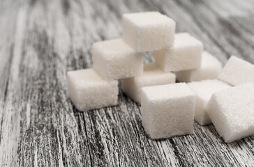 Sugar cubes lie on a wooden background of gray color. Sugar. Refined cane sugar