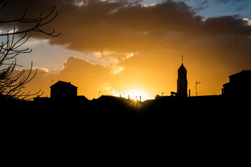 Silhouette of the town of Alfauir, in a beautiful sunset, with a cloudy sky and orange light.