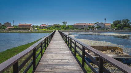 Obraz premium Wooden bridge between fishing ponds or lakes leading to residential suburbs of Nin with clear blue sky on sunny day, Croatia