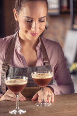 Barmaid serves two espresso martini coffee cocktails in a bar