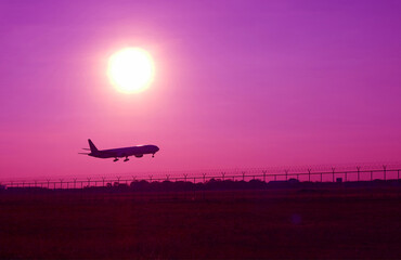 Pop art surreal styled silhouette of airplane taking off up to purple sky with bright sun