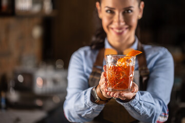 Old fashioned drink in ornamental glass offered by a female bartender in a pub - Powered by Adobe