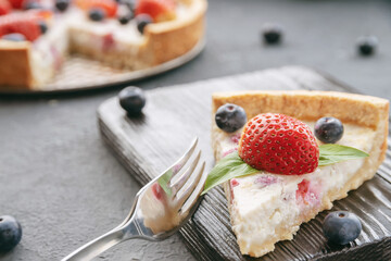 cheesecake with strawberries and blueberries on wooden stand or surface, close-up