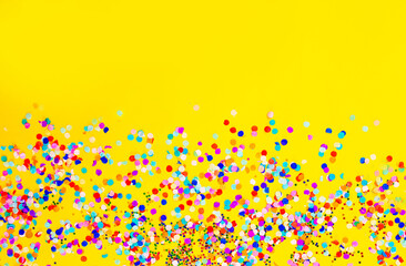lots of colored confetti on a yellow background