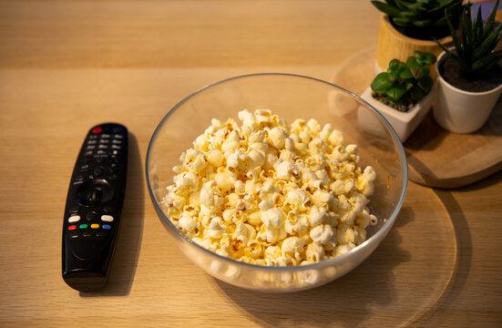 Movie Night. Popcorn Bowl And A Remote Control On The Wooden Table In The Living Room. 