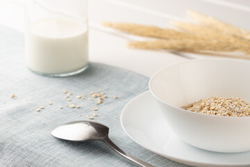 A healthy breakfast, a mixture of cereal flakes, muesli in a white bowl and milk in a bottle.