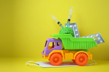 Home delivery of medicines ordered via the Internet. Bright toy car delivering vials and pills on the roof against a yellow background.