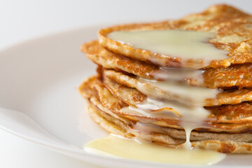 Plate with pancakes and condensed milk served on table. Dairy product. Delicious homemade breakfast.
