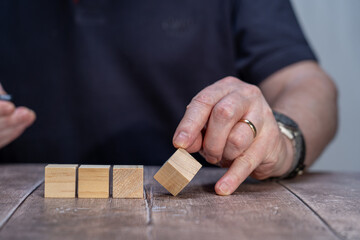 A mock up of Four blank timber block cubes three in a block with a man holding the end cube forming a multi faceted diamond shape