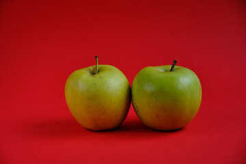 Two green apples on the red background