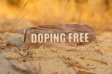 On the sand against a background of yellow grass a plate with the inscription -DOPING FREE