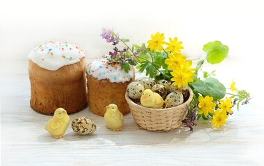 Fototapeta na wymiar Easter cakes, chickens toys, eggs and flowers on white wooden table. Spring festive season. traditional table holiday decor