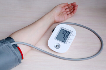 Woman measuring blood pressure with electronic digital tonometer, female hand close up. Arterial hypotension and cardiology concept