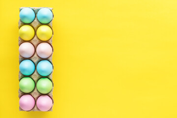 Easter colored eggs in box on yellow background. 