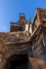 Fototapeta na wymiar Low point of view looking up at a wooden mining head frame with mine entrance directly ahead