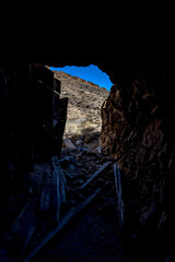 Looking out of a mine shaft filled with leftover mining equipment and garbage into the daylight