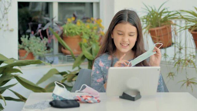 joven bella realizando una conferencia por ordenador ense&ntilde;ando varias mascarillas