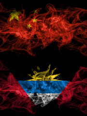 China, Chinese vs Antigua and Barbuda, Antiguan and Barbudan smoky mystic flags placed side by side. Thick colored silky abstract smoke flags.
