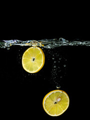sliced lemon falling in the water on dark background. Underwater view. Cooking, vegetarian, cooking at home concept