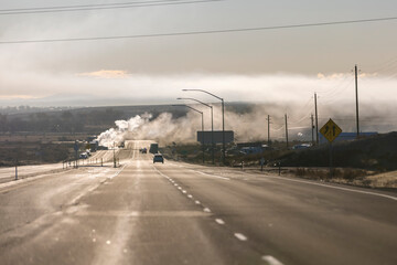 Far away backlit smoke scene from a semi truck trailer fire on the side of a highway
