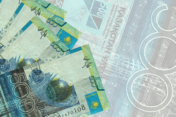 500 Kazakhstani tenge bills lies in stack on background of big semi-transparent banknote. Abstract...