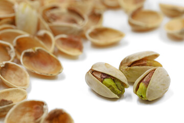 three pistachio nuts in heap of shells on a white background