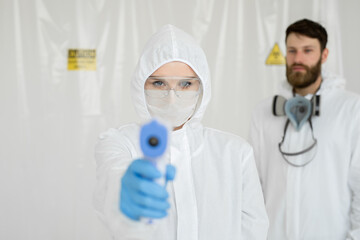 Medical professionals in protective clothing measuring contactless fever at Covid-19 test center during coronavirus epidemic.